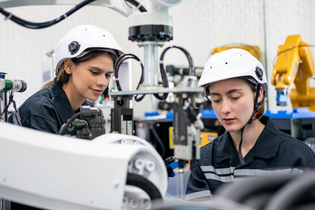 Female Engineer check and control automation robot arms machine in factory. robotics manufacturing.